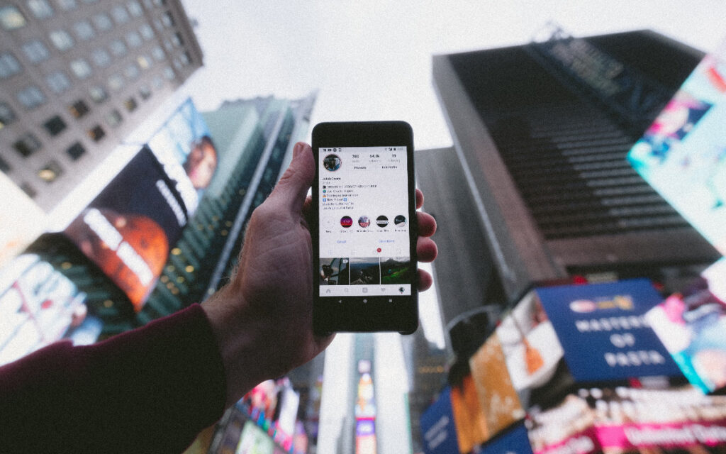 Person holding up phone in middle of city, which is a business IT trend in recent years.