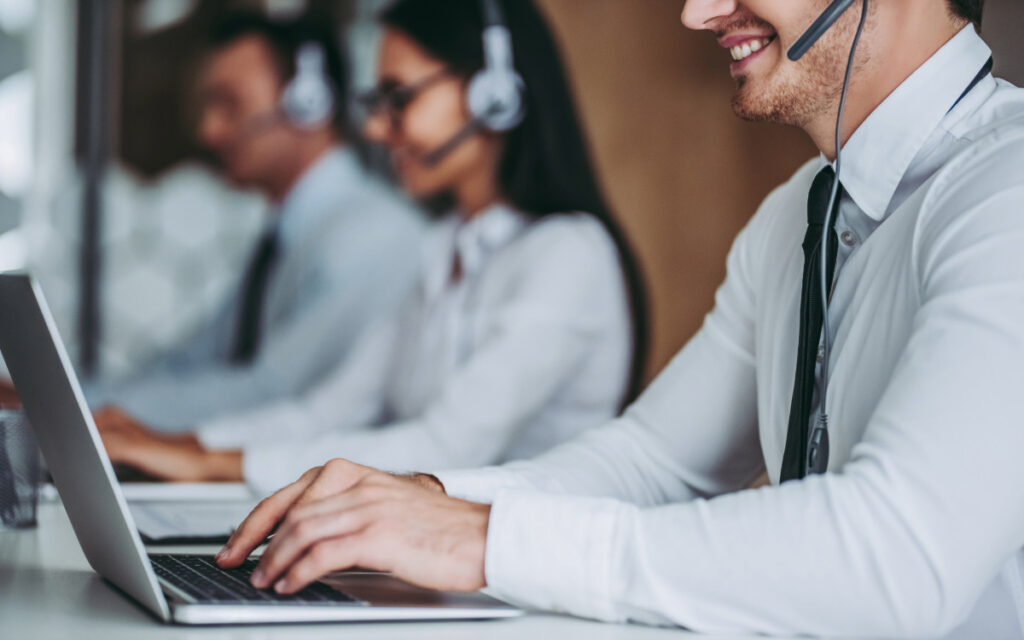 3 people with headsets and laptops providing outsourced IT help desk services.