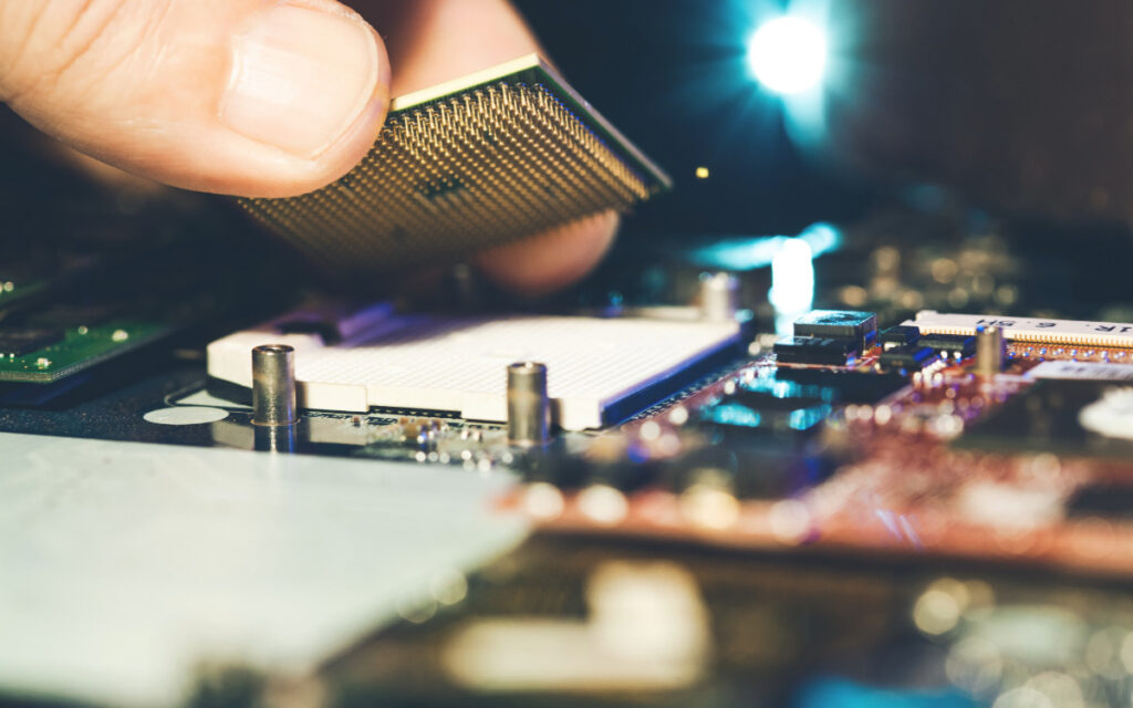 A hand putting a CPU on a motherboard being replaced due to Windows 10 end-of-life.