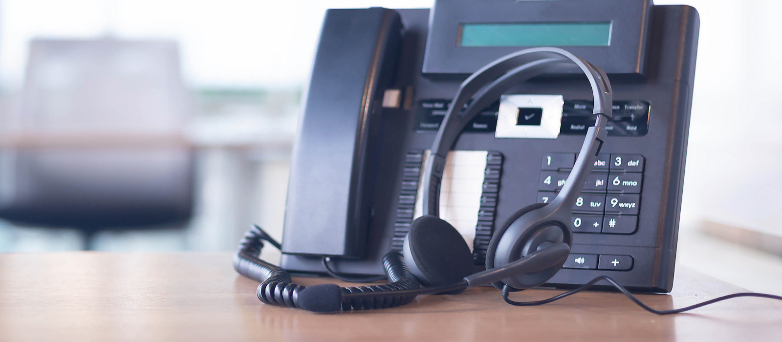 A phone with a headset on a desk which can be used to call remote IT services.