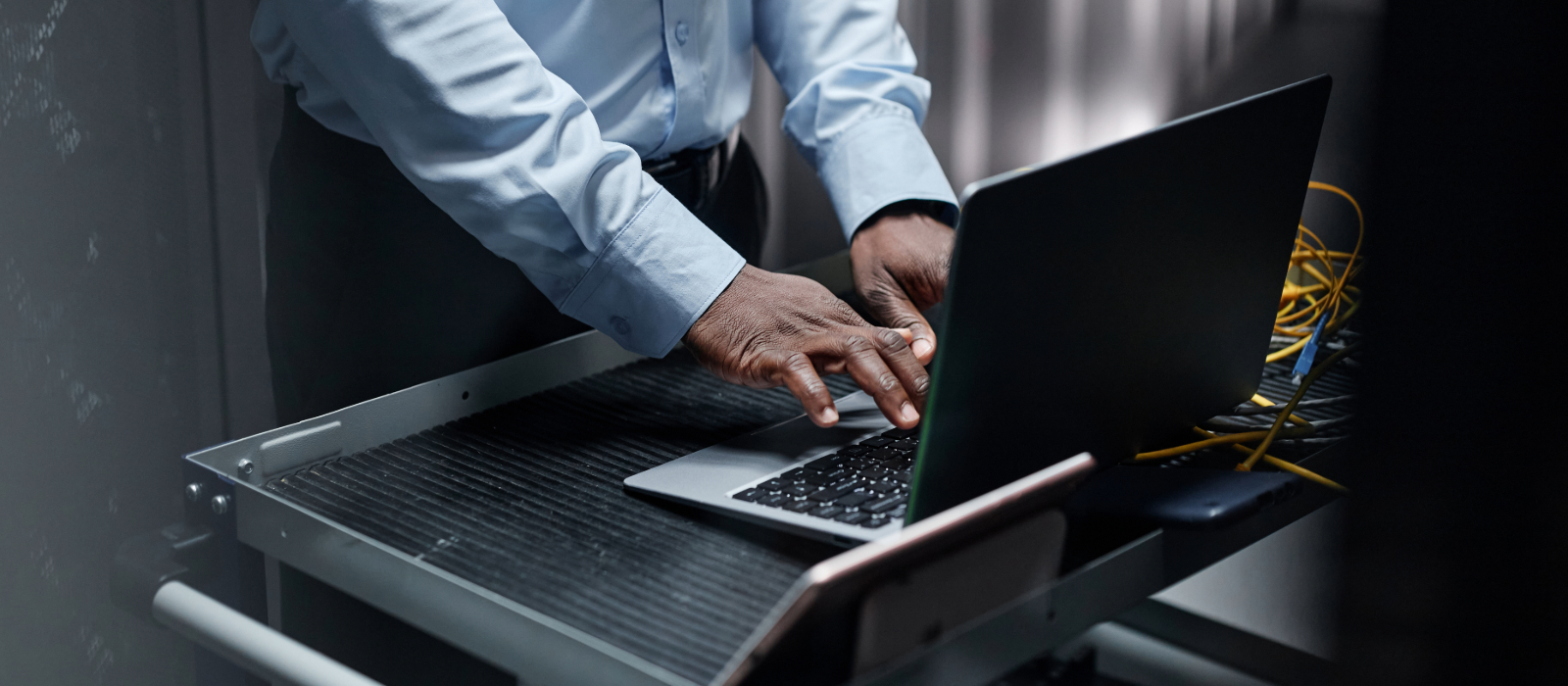 I man using a laptop on a mobile desk doing an IT compliance audit.