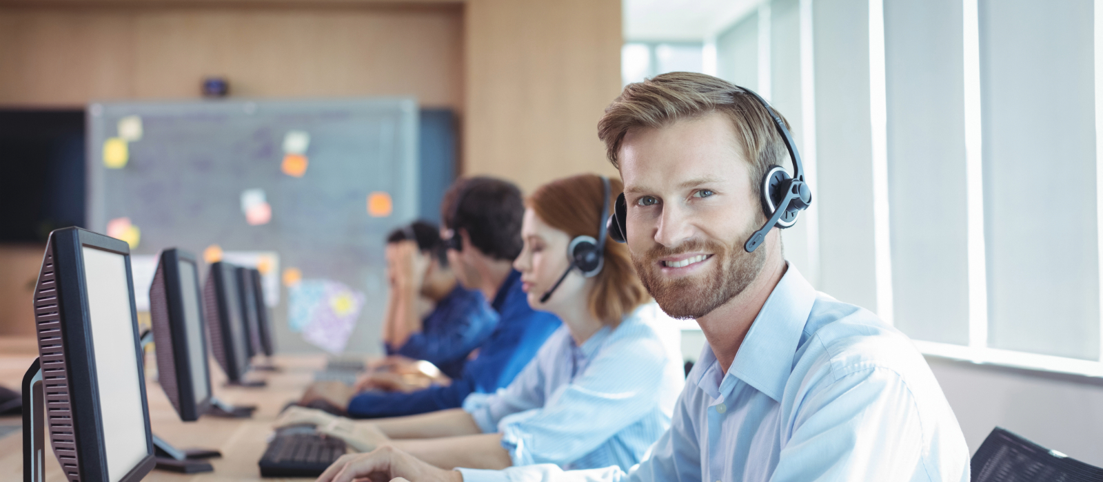 A group of people sitting at computers wearing headsets using a cloud-based phone system.