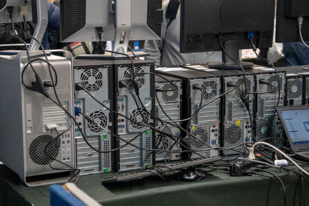 Back view of an old computer wall with tangled cables and outdated hardware, representing the need for legacy system modernization.