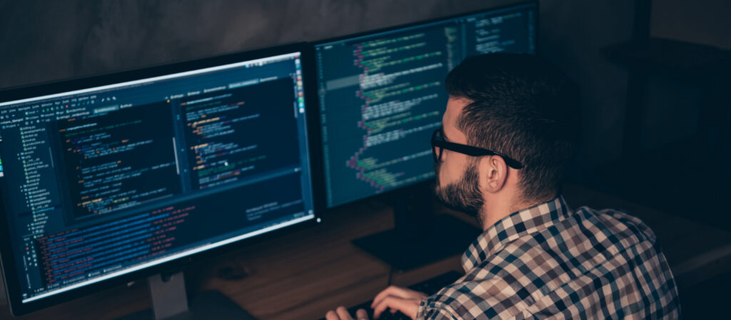 IT specialist at a workstation with dual monitors helping with onboarding.
