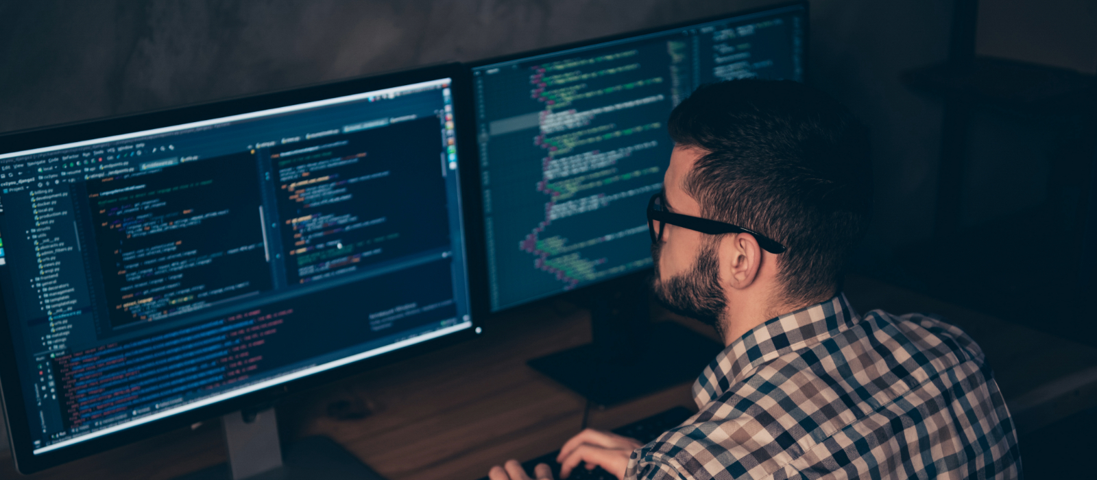 IT specialist at a workstation with dual monitors helping with onboarding.
