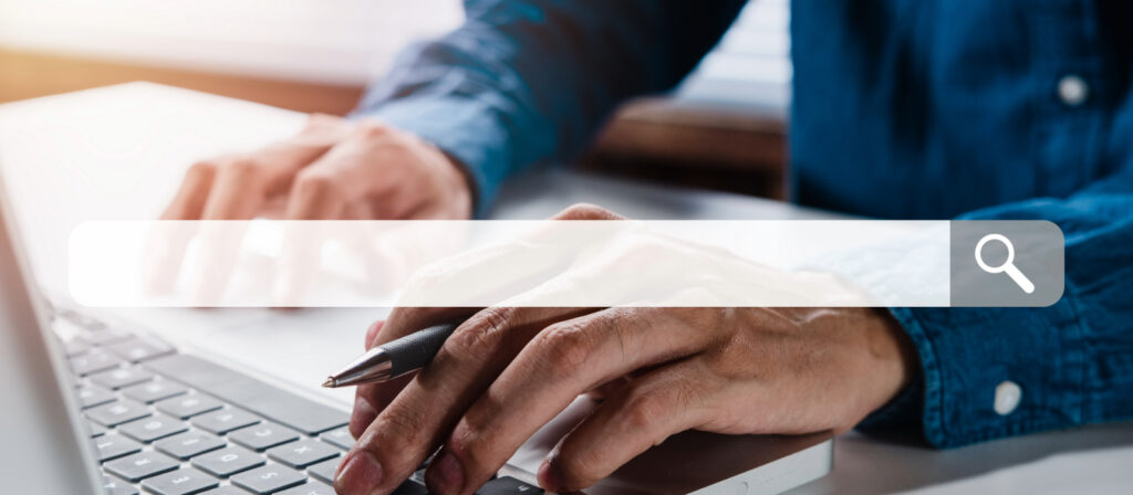 Person typing on a laptop with a search bar overlay, representing someone searching for information through a web browser.
