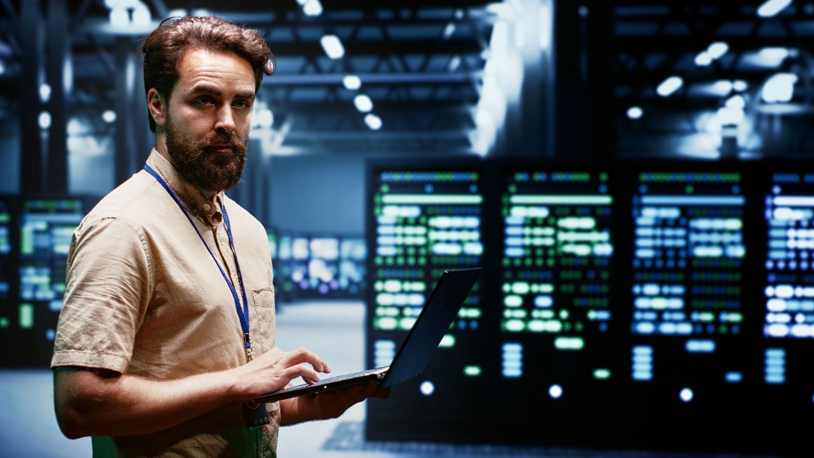 An IT professional working on a laptop in a server room, representing IT redundancy through reliable systems and data protection.
