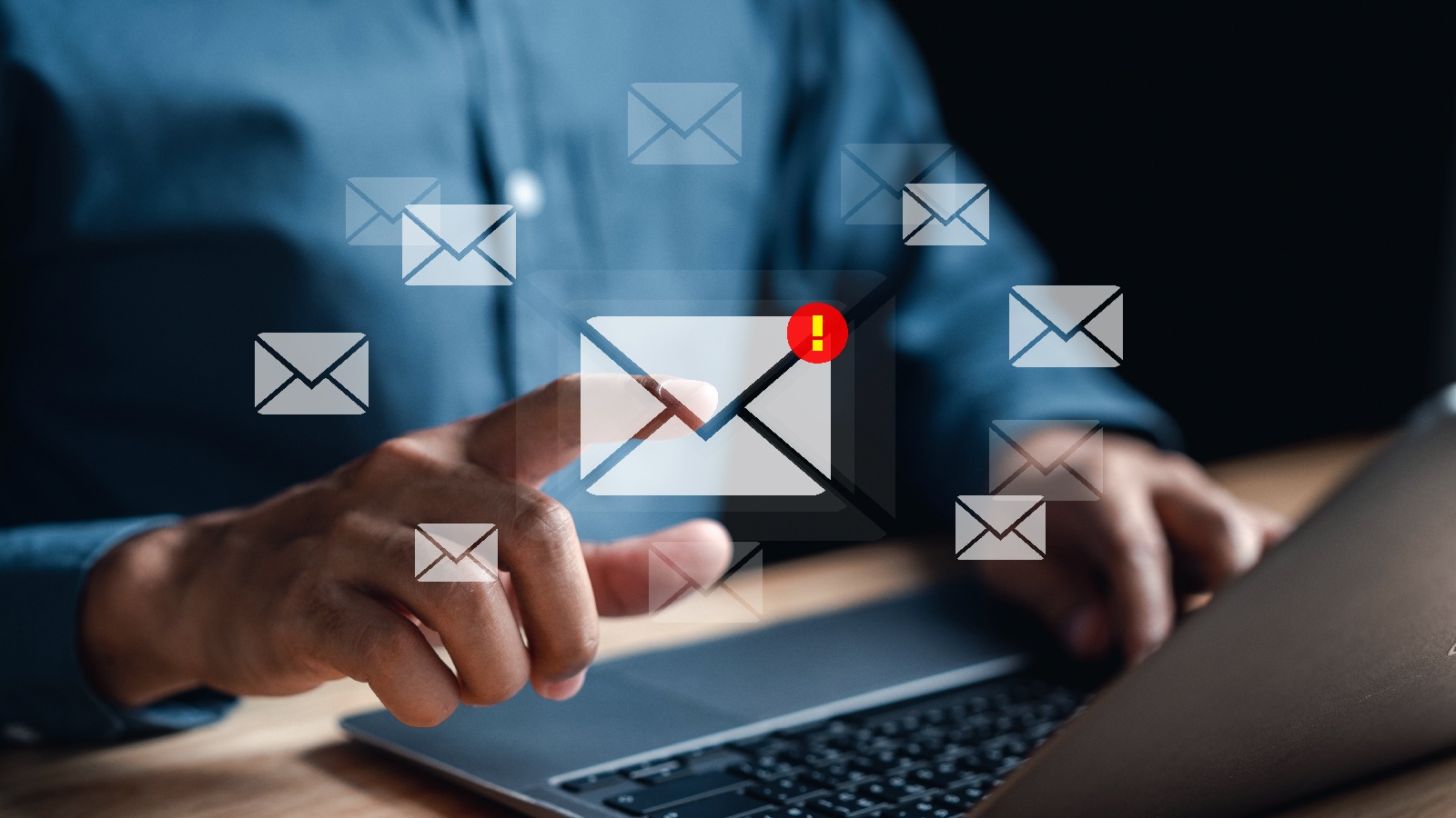 A person using a laptop with digital email icons and a warning symbol, representing phishing training and the risks of suspicious emails.