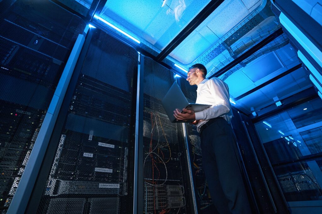 IT professional inspecting server equipment in a data center using a laptop.