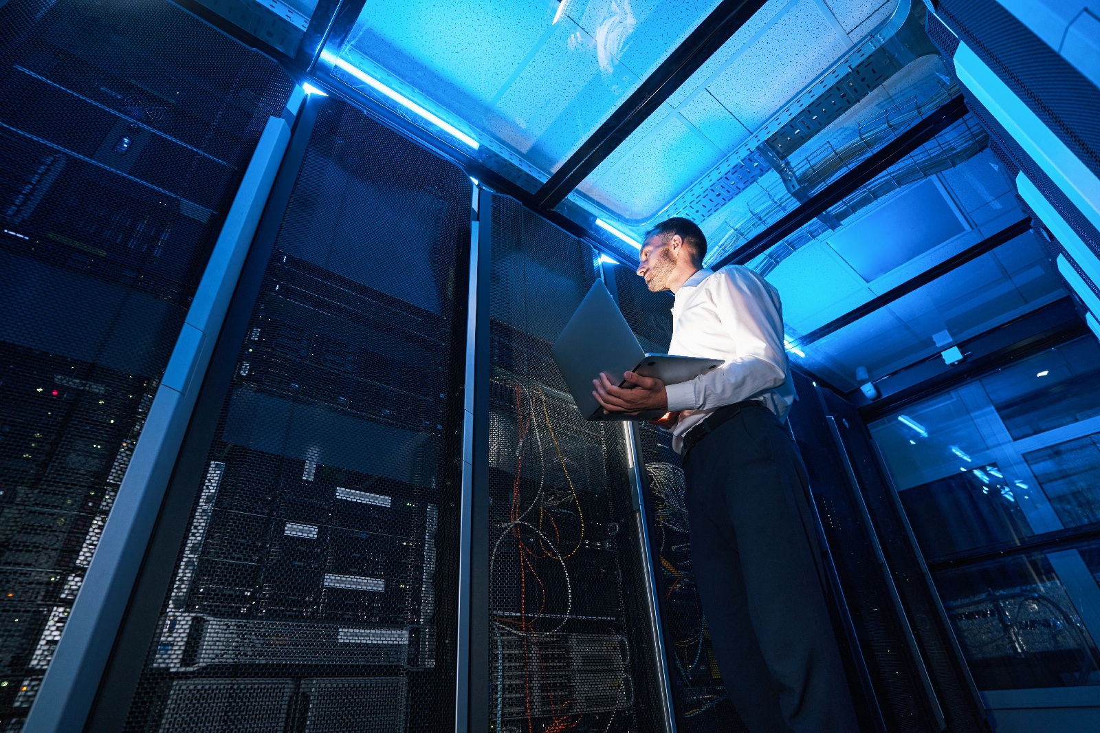 IT professional inspecting server equipment in a data center using a laptop.